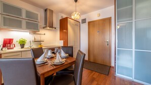 A modern kitchen with wooden cabinets, a dining table set for four, and a sliding glass door leading to a balcony. - Vacation apartment by the sea, vacation on the island of Usedom, Apartment WIND ROSE 33 (Świnoujście)