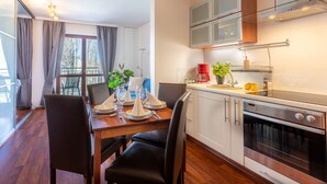 A modern kitchen with a dining area, stainless steel appliances, and a large window with curtains. - Vacation apartment by the sea, vacation on the island of Usedom, Apartment WIND ROSE 33 (Świnoujście)