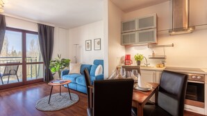 A modern living room with a blue sofa, a dining table, and a kitchen area with a stove and cabinets. - Vacation apartment by the sea, vacation on the island of Usedom, Apartment WIND ROSE 33 (Świnoujście)