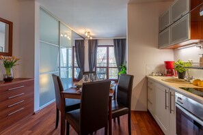 Une cuisine moderne avec un coin repas, des meubles de rangement en bois, un évier et une fenêtre avec des rideaux.