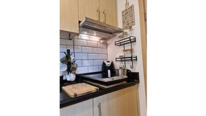 Eine Küche mit Holzausstattung, einer schwarzen Arbeitsplatte, einer Edelstahl-Dunstabzugshaube und einem an der Wand befestigten Küchenutensilienhalter.