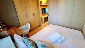 Ein modernes Hotelzimmer mit einem großen Bett, einem Schreibtisch und einem Kleiderschrank.