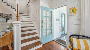 A staircase with white railings and wooden steps leading to a blue door. - Private Pool + Whimsical Sleeping Porch Steps from Beach by Tybee Cottages (Tybee Island)