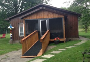 A wooden cabin with a porch, a ramp, and a bench. - Country Atmosphere -  City amenities,   Minutes to downtown (Peterborough)