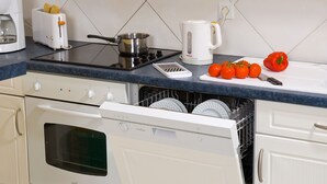 A kitchen with a stove, toaster, kettle, and a dish rack with dishes. - Résidence Madame Vacances Les Appartements de Fontenelles (L'Aiguillon-sur-Vie)