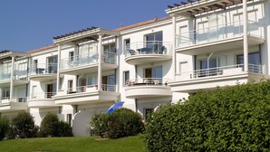 A multi-story residential building with balconies, large windows, and a clear sky. - Résidence Madame Vacances Les Appartements de Fontenelles (L'Aiguillon-sur-Vie)