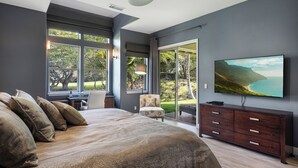 A modern bedroom with a large bed, a TV, and a view of the outdoors.