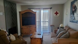 A living room with a fireplace, a sofa, a coffee table, and a television. - 1205  Pool, Hot tub, sauna - The Relaxing Shed (Beech Mountain)