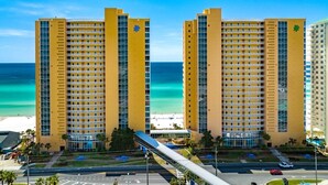 Un hotel amarillo con vista a la playa, varios pisos y balcones.
