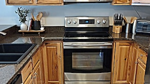 Una cocina con armarios de madera, electrodomésticos de acero inoxidable y piso de baldosas.
