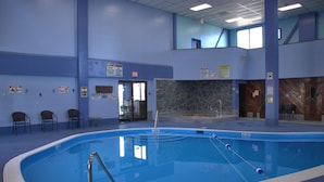 Una piscina interior con pared de piedra, varios carteles y sillas a lo largo del borde.