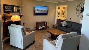 A living room with a flat-screen TV, two armchairs, a coffee table, and a fireplace. - 2116  Mystic Mountain View - Hot tub, sauna & more resort amenities (Beech Mountain)