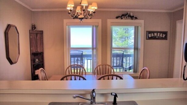 A kitchen with a double sink, a chandelier, and a dining area with chairs and a table. - 2116  Mystic Mountain View - Hot tub, sauna & more resort amenities (Beech Mountain)