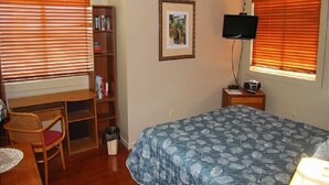 A bedroom with a bed, a desk, a chair, a bookshelf, a television, and a window with blinds. - 4216  Hot tub, sauna & more resort amenities  Northview Retreat (Banner Elk)