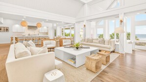Amplia sala de estar con un sofá blanco grande, una mesa de centro y un comedor con muebles de madera.