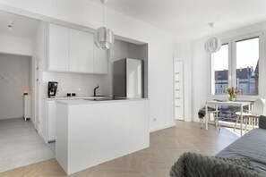 A modern kitchen with white cabinetry, a central island, and a dining area with a table and chairs.