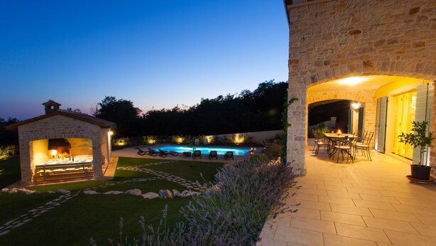 A stone building with a pool, outdoor seating, and a well-maintained lawn. - Villa Vista Azzurra with pool, summer kitchen and well-tended garden (Sveti Lovreč)