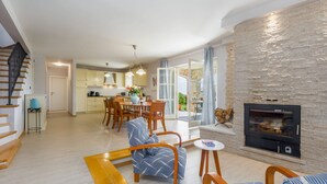 A spacious living room with a fireplace, a dining area with a kitchen in the background, and a staircase leading to another level. - Villa Vista Azzurra with pool, summer kitchen and well-tended garden (Sveti Lovreč)