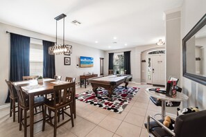 A living room with a pool table, dining table, and chairs.