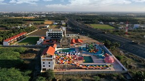 An aerial view of a resort with a swimming pool, water slides, and a road running alongside. - Pride Divine Resort Somnath (Veraval)