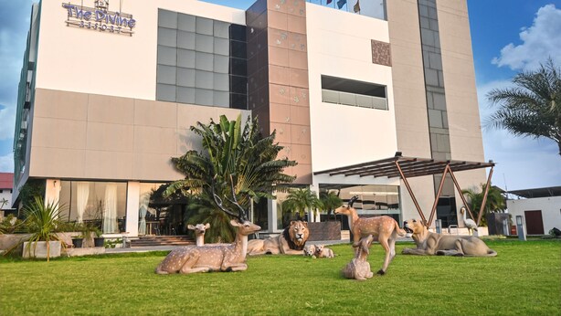 The Divine Resort with a modern building, a grassy lawn, and various animal sculptures. - Pride Divine Resort Somnath (Veraval)