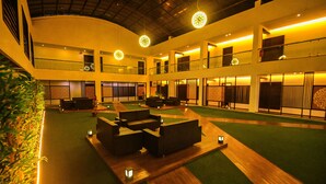 A spacious lobby with a central seating area, multiple balconies, and a high ceiling. - Pride Divine Resort Somnath (Veraval)