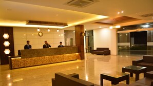 A hotel reception area with a marble reception desk, modern lighting, and seating arrangements. - Pride Divine Resort Somnath (Veraval)