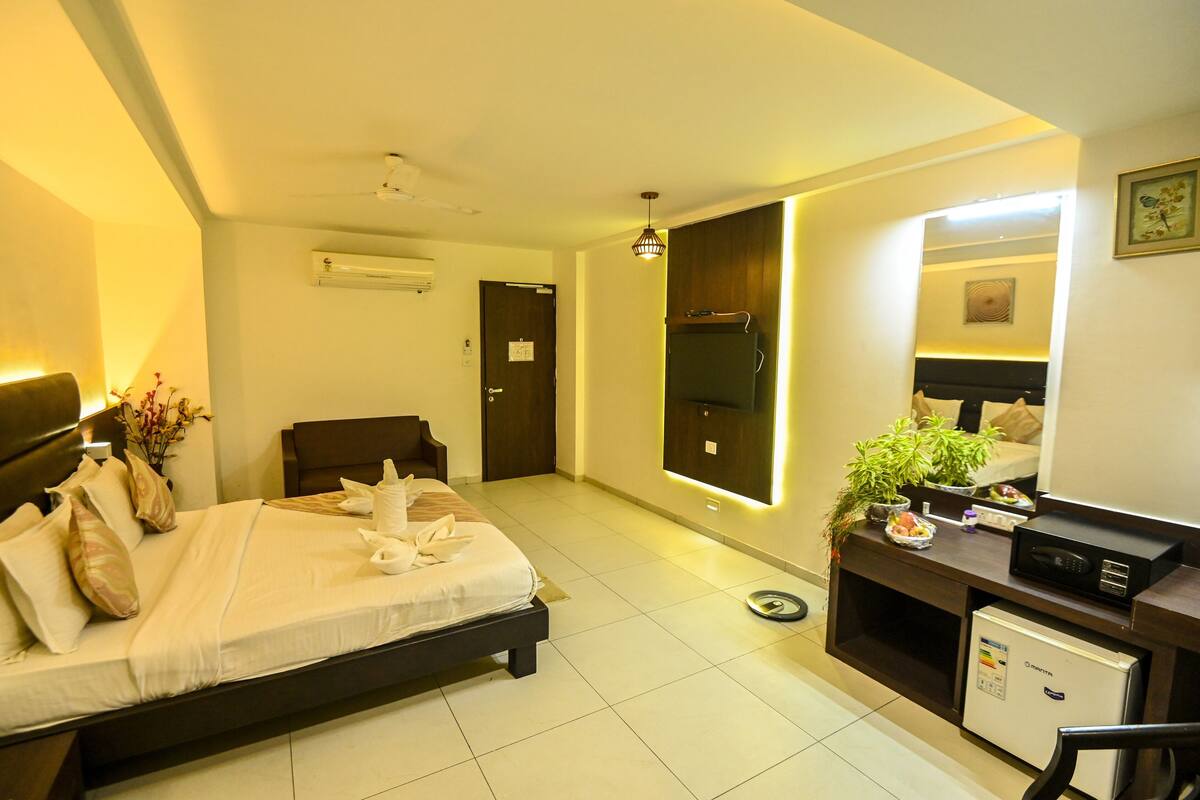 A hotel room with a bed, bedside table, and a small refrigerator.