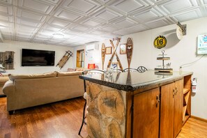 Ein Wohnzimmer mit Kücheninsel aus Stein, einem Flachbildfernseher, Skiern und einem Schild für 'Devils Backbone Brewing Company'.
