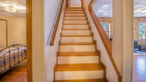 A wooden staircase with a handrail, leading to a door with a geometric pattern.