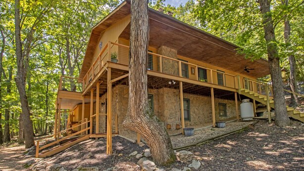 A wooden cabin with a stone exterior, a balcony, and a staircase leading to the upper level.