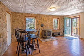 Enjoy a warm gathering by the stone fireplace in this cozy room, featuring a dining table and chairs.