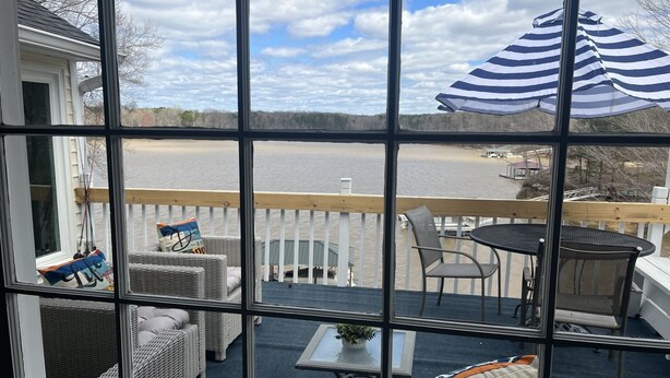 Una terrazza con mobili in vimini, un tavolo e vista su un lago.