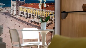 A balcony with a view of a historic building, a white chair, and a potted plant. - Vita Portucale | Downtown Premium with Garage (Lisboa)