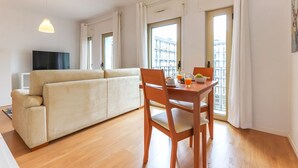 Una sala moderna con sofá, mesa de comedor, sillas y televisor.