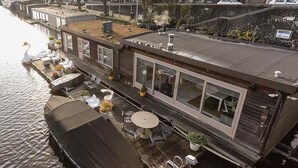 Une péniche flottante dotée d’un espace extérieur aménagé et d’une zone couverte.
