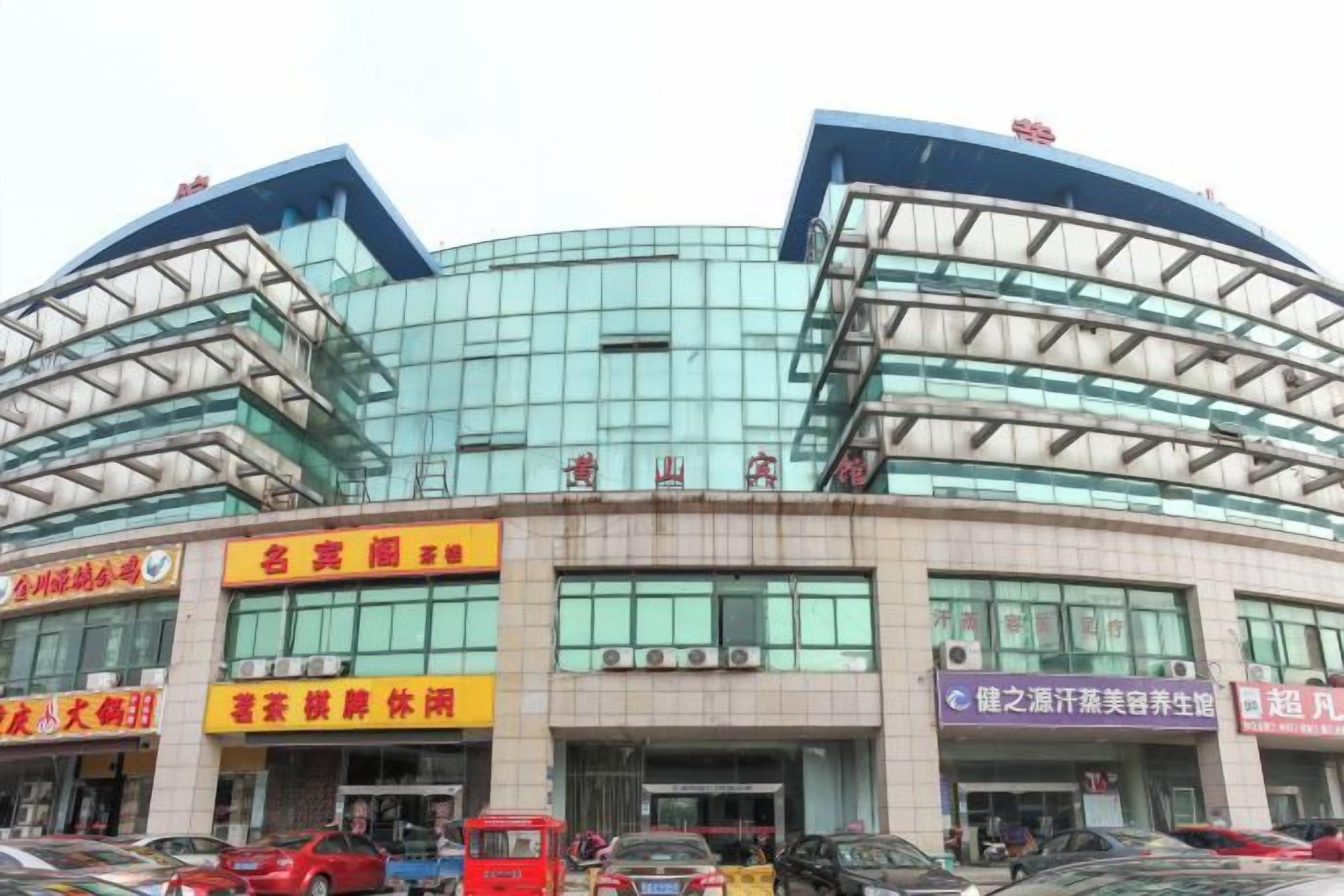 A modern building with multiple commercial establishments on the ground floor, featuring large glass windows and a curved architectural design.
