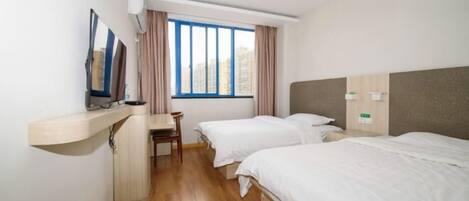 Habitación de hotel con dos camas individuales, un escritorio, una silla y un amplio ventanal con cortinas.