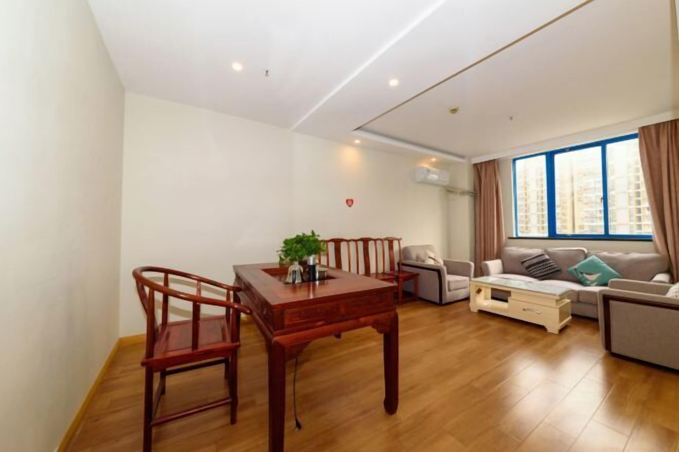 A modern living room with a wooden dining table, two chairs, a sofa, and a coffee table.
