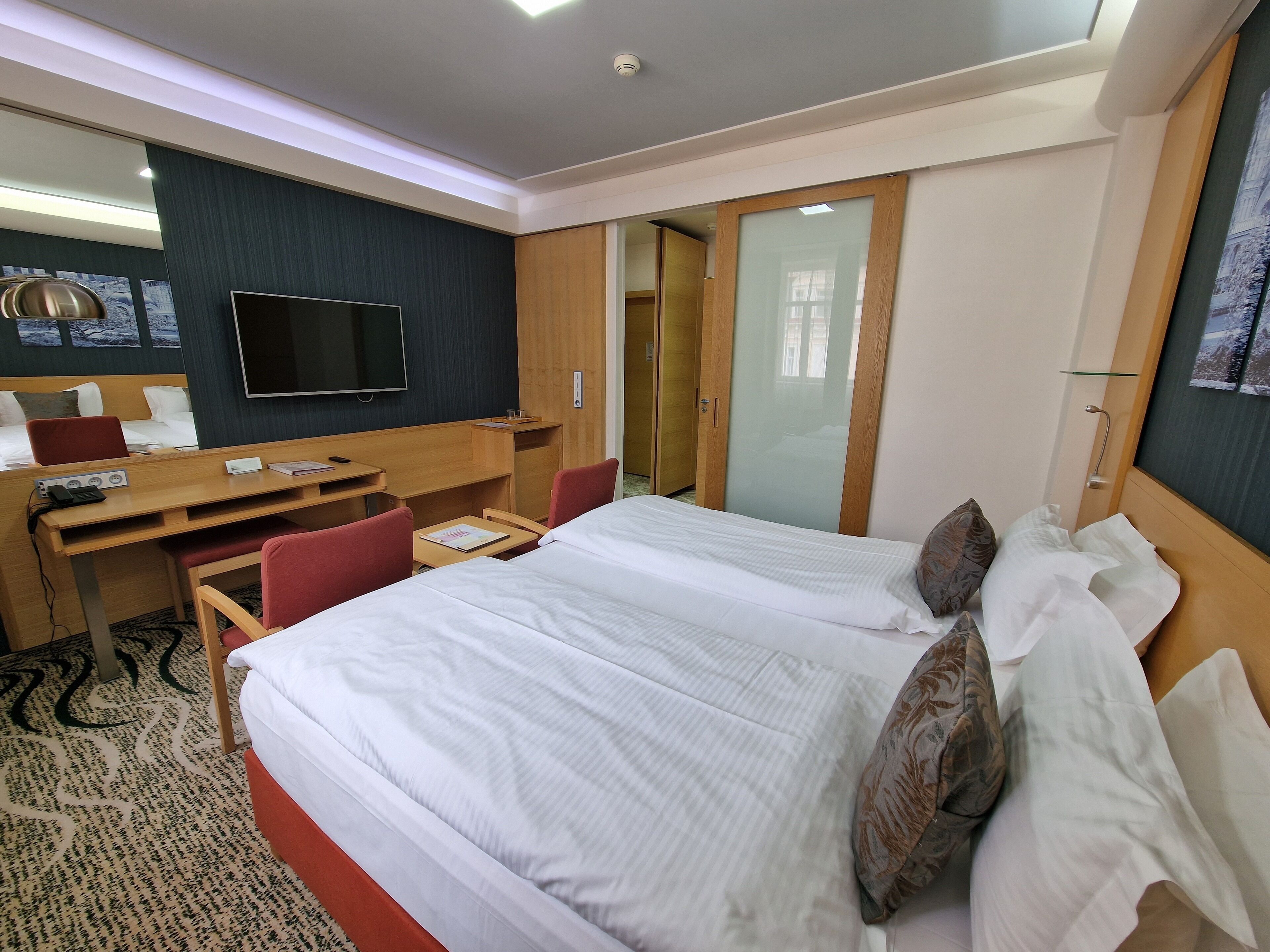 Une chambre d’hôtel équipée d’un lit, d’un bureau, de chaises, d’une télévision et d’une armoire.