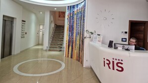 Un área de recepción moderna con techo curvo, una escalera y un mostrador de recepción identificado como "iris".