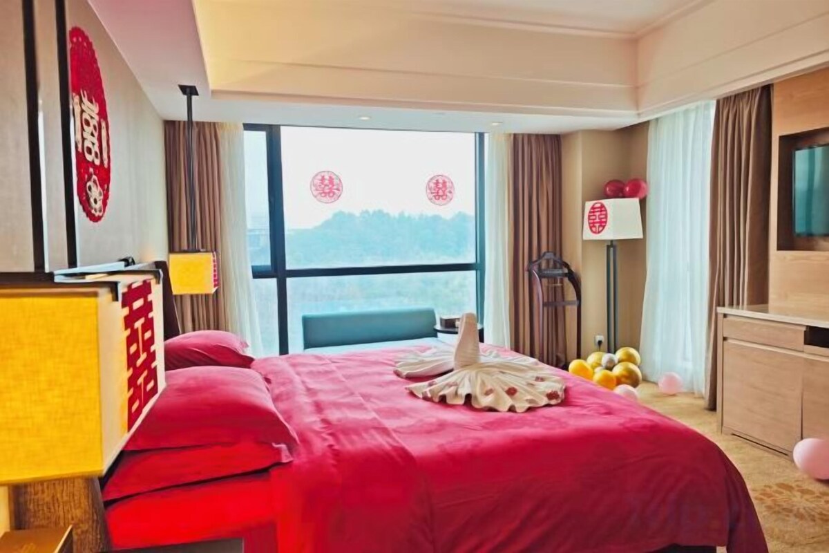 Habitación de hotel con una cama grande, un escritorio, una silla, un televisor y una ventana con vistas.