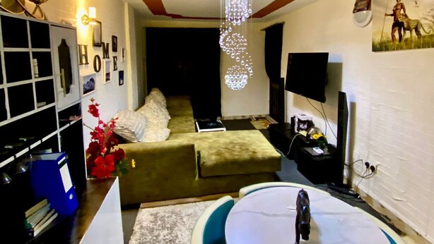 A cozy living room with a sofa, a coffee table, and a TV. - Stay.Plus Kings & Queen's Apartment (Nairobi)