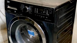 A black front-loading washing machine with a digital display and control panel. - Stay.Plus Kings & Queen's Apartment (Nairobi)