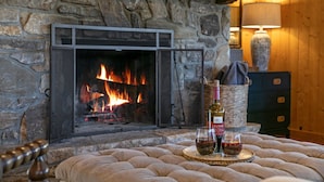 A stone fireplace with a lit fire, a bottle of wine, and two glasses on a tray. - Beautiful view with firepit and hot tub. Only 7 minutes to Cashiers and Glenville! (Cashiers)