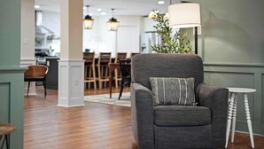 Una sala de estar moderna con un sillón gris, una mesita auxiliar blanca y una lámpara de pie.