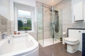 A modern bathroom with a glass-enclosed shower, a freestanding bathtub, and a toilet.