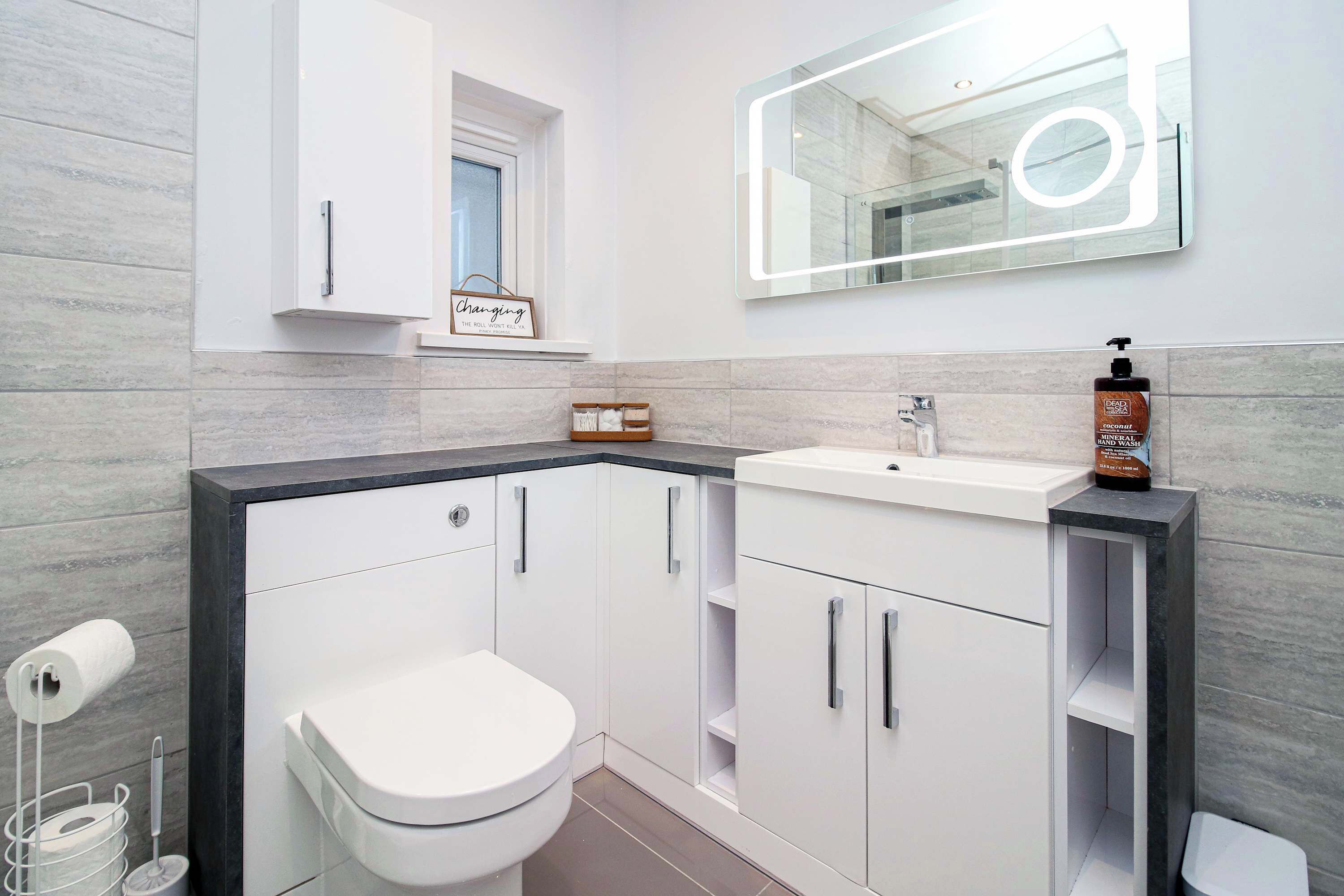A modern bathroom with a toilet, sink, and mirror.