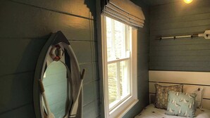 A bedroom with a bed, a window, a mirror, and a wall-mounted shelf with a starfish and a seashell. - The Cornish Peak: Cornwall by STAE-Homes (Cornwall)
