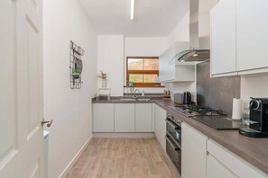 A compact kitchen with white cabinets, a wooden countertop, a gas stove, and a window with a view of the outdoors.